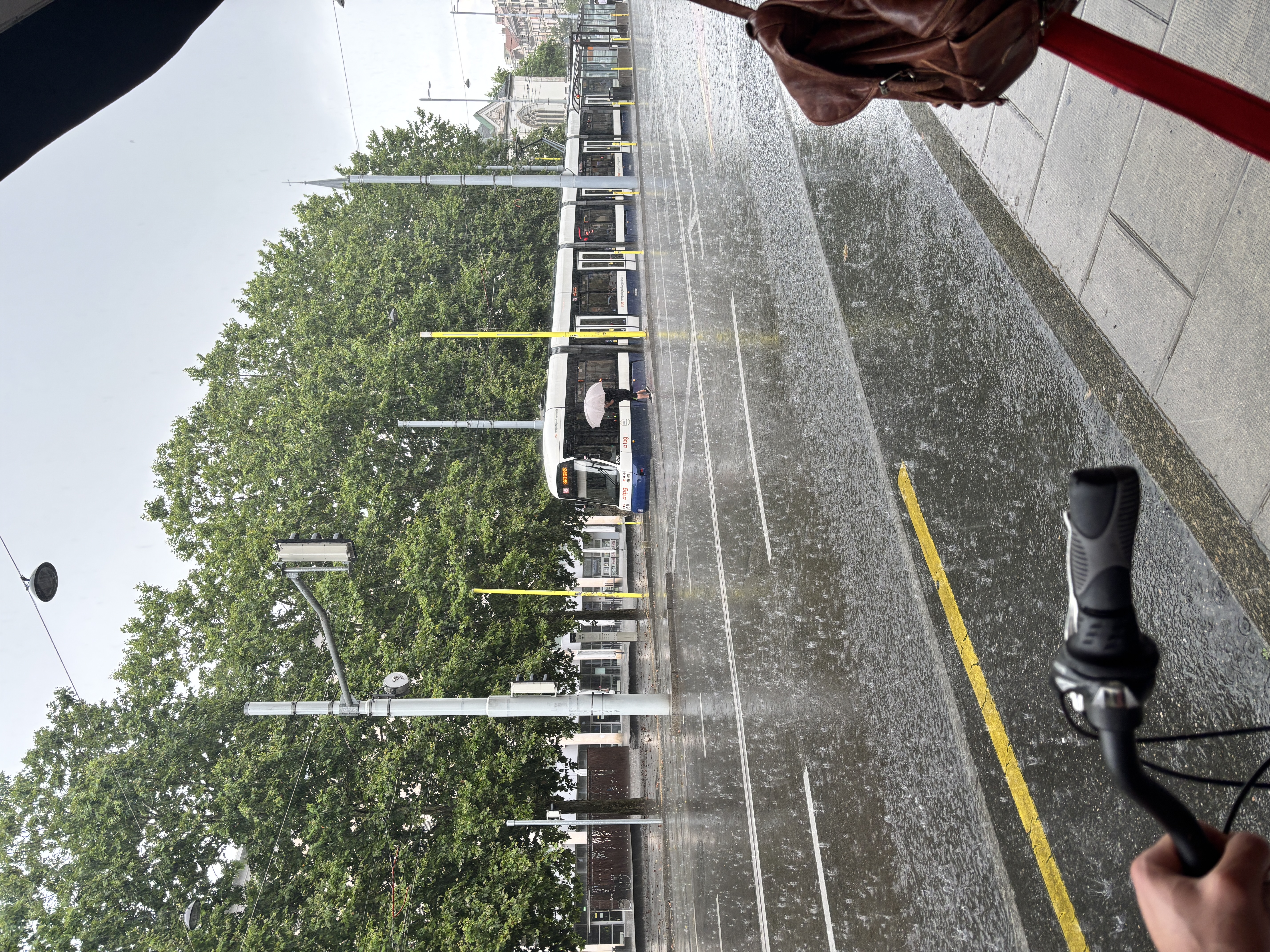 Rainy Geneva street with a tram and overhead wires