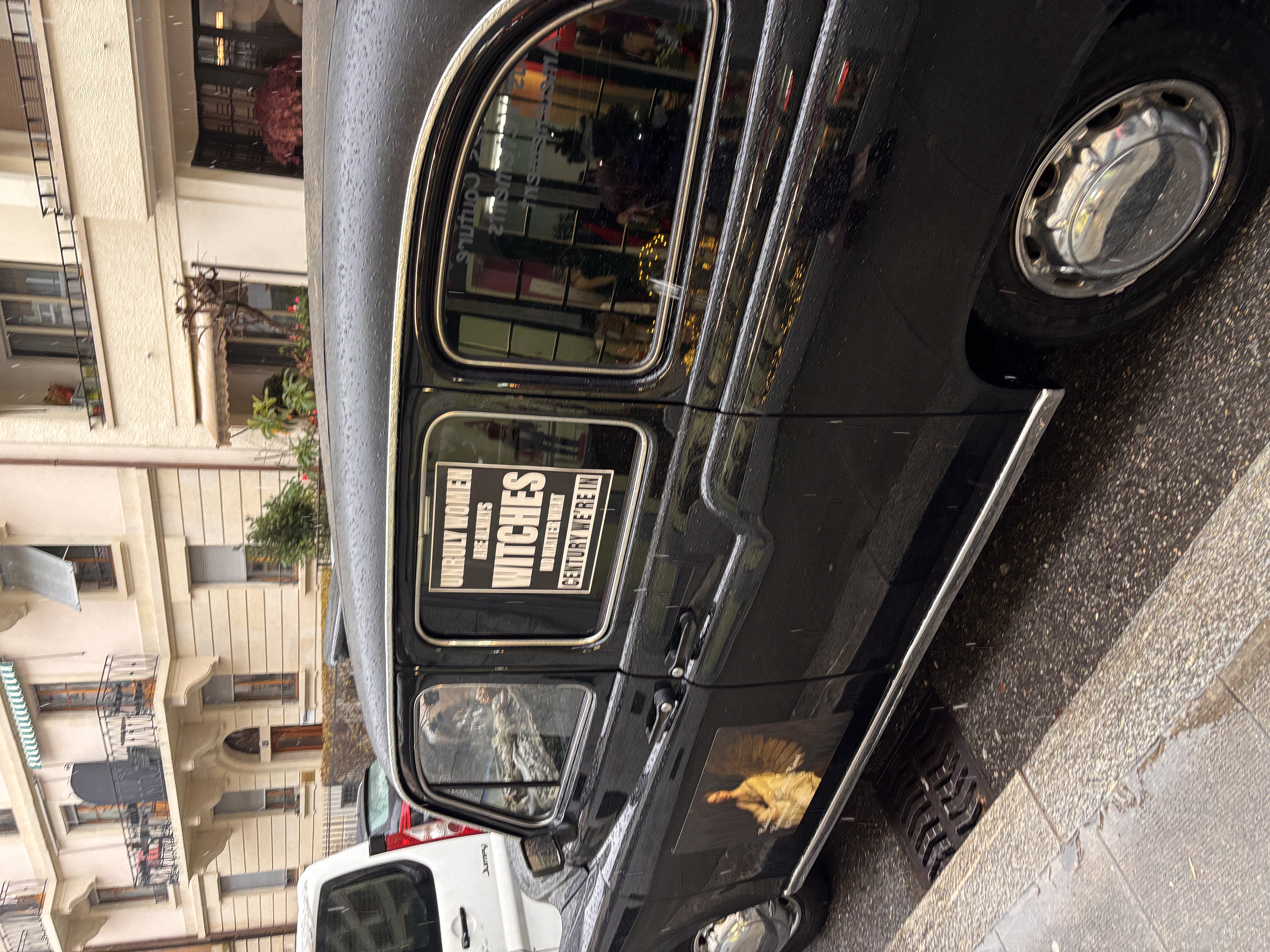 Black car on a Geneva street with a theatre poster